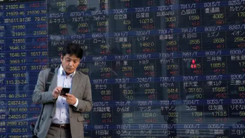 Getty Images Man stands in front of stock boards in Japan