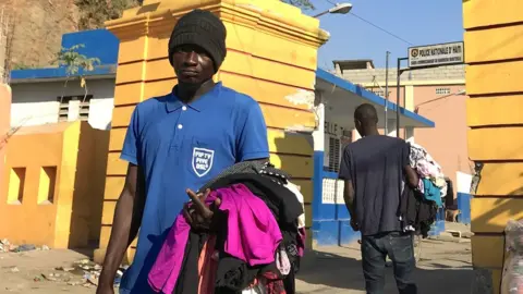 Gemma Handy A man sells second-hand clothes on the streets in Haiti
