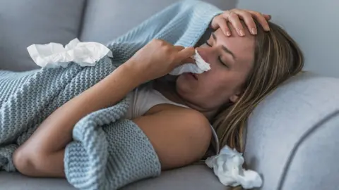 Getty Images Women ill at home on the sofa with flu