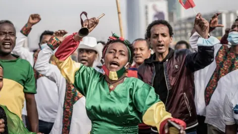 Getty Images People hold flags as they shout slogans in Addis Ababa, Ethiopia, on September 6, 2021, during a ceremony held to support the Ethiopian military that is battling against the Tigray People's Liberation Front (TPLF) in the Amhara and Afar regions