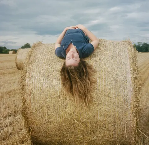 Joanne Coates Poppy, a vet and farmer's daughter, lies across a hay stack at her home farm near Foulden in the Scottish Borders