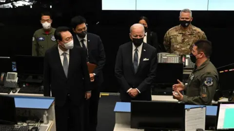 Getty Images US President Joe Biden (centre R), accompanied by South Korea's President Yoon Suk-yeol (centre L), tours the Air Operations Centers Combat Operations Floor at Osan Air Base in Pyeongtaek on May 22, 2022