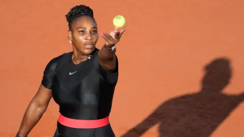 Getty Images Serena Williams stares up at ball as she prepares to serve on a clay court