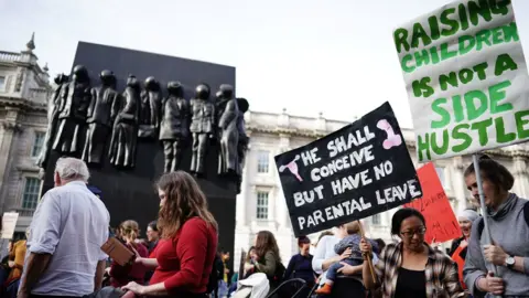 PA Media Demonstrators take part in a march in central London demanding reform of childcare, parental leave and flexible working