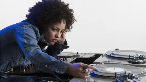 Getty Images Stock image of a woman DJ-ing at a set of record decks