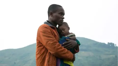 AFP A Congolese man holds his child after he crossed the border from the Democratic Republic of Congo (DRC) to be refugees at Nteko village in western Uganda on January 24, 2018.