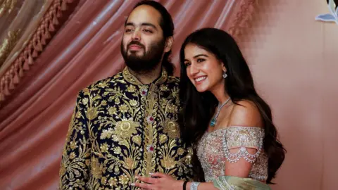 Reuters Anant Ambani, son of businessman Mukesh Ambani, poses with his fiance Radhika Merchant on the red carpet during the sangeet ceremony at Jio World Centre, Mumbai, India, July 5, 2024