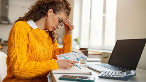 Getty Images Woman looks at bills