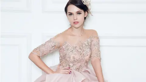 Stella Lunardy Couture A model wearing a rose gold gown