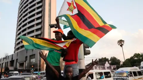 AFP People holding Zimbabwean flags celebrate in the street after the resignation of Robert Mugabe as president on 21 November 2017 in Harare, Zimbabwe