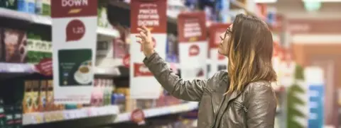 Getty Images Woman choosing products in a supermarket aisle