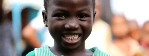 Tunde Onakoya Young Nigerian girl holds chess piece and smiles wearing green shirt