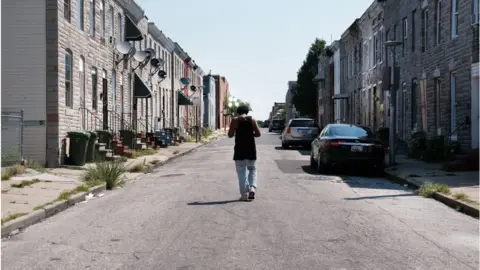 Getty Images A man walks down a Baltimore street near where a person was recently murdered on July 28, 2019 in Baltimore, Maryland