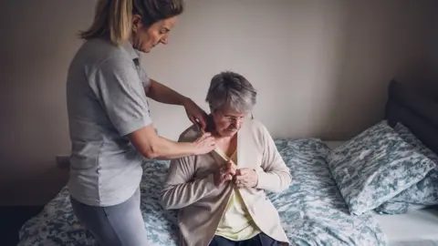 Getty Images A carer helping a female client in her bedroom