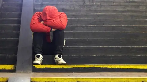 Getty Images Young homeless man sitting on steps.