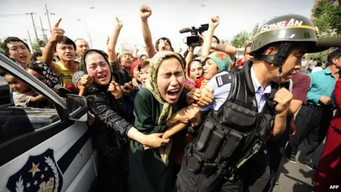 AFP Uighur women grab a riot policemen as they protest in Urumqi in China's far west Xinjiang province on July 7, 2009