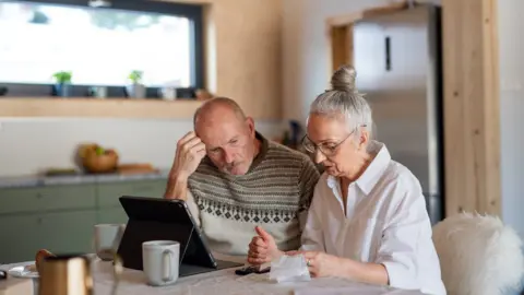 Getty Images (stock image) man and a woman at a kitchen table