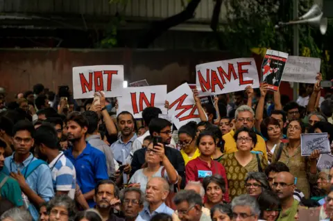 Getty Images Indian protesters hold placards as they gather during a 'Not in my name' protest in Delhi in June 2017