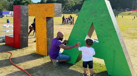 Brandon Drenon/BBC Torino Henry signs an art installation at Atlanta's Juneteenth celebration