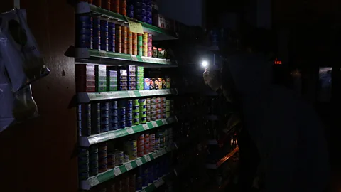 Getty Images People use phones to illuminate goods in a supermarket in Buenos Aires, Argentina during a power cut (Credit: Getty Images)
