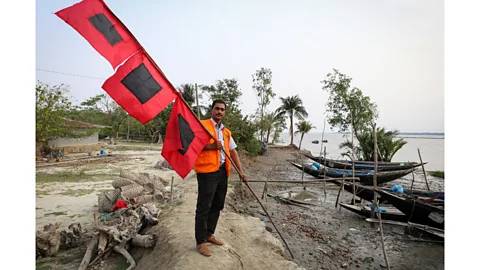 Catherine Davison Sabastin Bachar, team leader of CPP for Chila village, shows the three-tiered flag system which is displayed in the village square (Credit: Catherine Davison)
