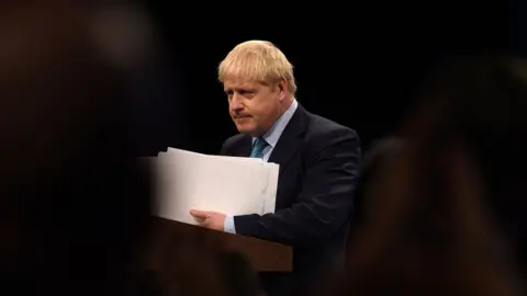 Getty Images Boris Johnson seen holding papers from the viewpoint of delegates at the Conservative Party conference