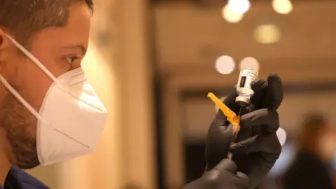 Getty Images A medical worker fills a syringe with a Covid vaccine