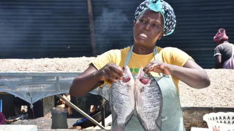Viola Kosome Esther Ongowe holds fish at the Dunga beach fish market in Kisumu