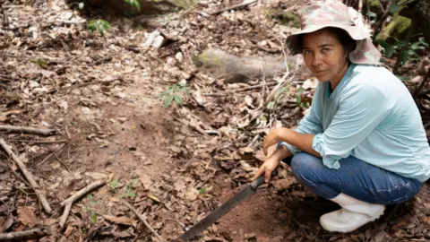 BBC/Paulo Koba Catarina Oliveira de Silva points down at what used to be a lake