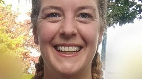 Family photo A woman smiling at the camera. She has blonde hair in pigtails.