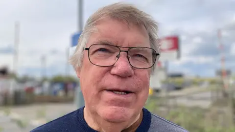 BBC / Sarah Sanderson David Harby has light-colored hair and wears glasses and a blue and grey top