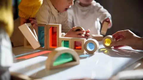 Getty Images Children playing with wooden blocks with different coloured plastic in the middle in a childcare setting