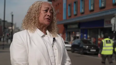 Liverpool Riverside MP Kim Johnson, wearing a white blouse and jacket, stands outside Arndale House in Liverpool city centre. 