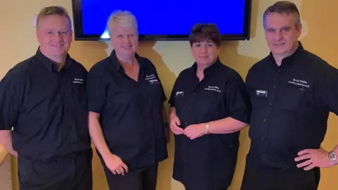 Andrew Poole A picture of cinema staff in black shirts - two men on the outside and two women in the middle