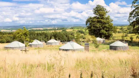 Getty Images A sunny field filled with yurts.
