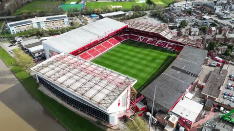 PA A bird's eye view of Nottingham Forest's City Ground. It shows the green grass and red stands, with the words NFFC, and rooftops of homes nearby