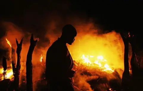 Getty Images A Sudanese rebel fighter sombrely watches the abandoned village of Chero Kasi burn less than an hour after Janjaweed militiamen set it ablaze in the violence plagued Darfur region on 7 September 2004
